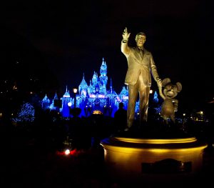 disneyland castle at night with walt and mickey in the foreground
